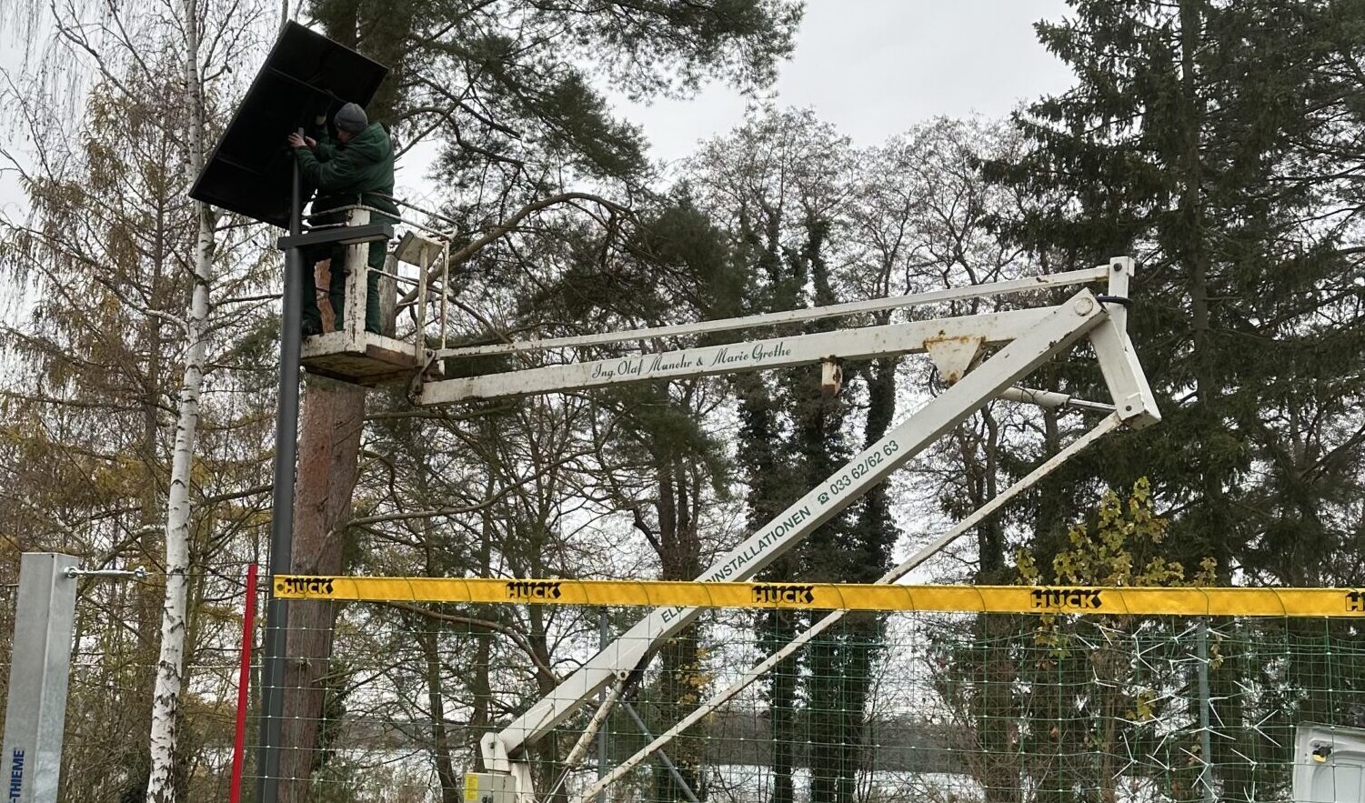 Fachmännische Hilfe: Björn Meyke und Roman Galinski von der Elektro Manohr installieren die Leuchte am Volleyballfeld neben dem Robert-Havemann-Klubhaus. Foto: Felix Jahnke
