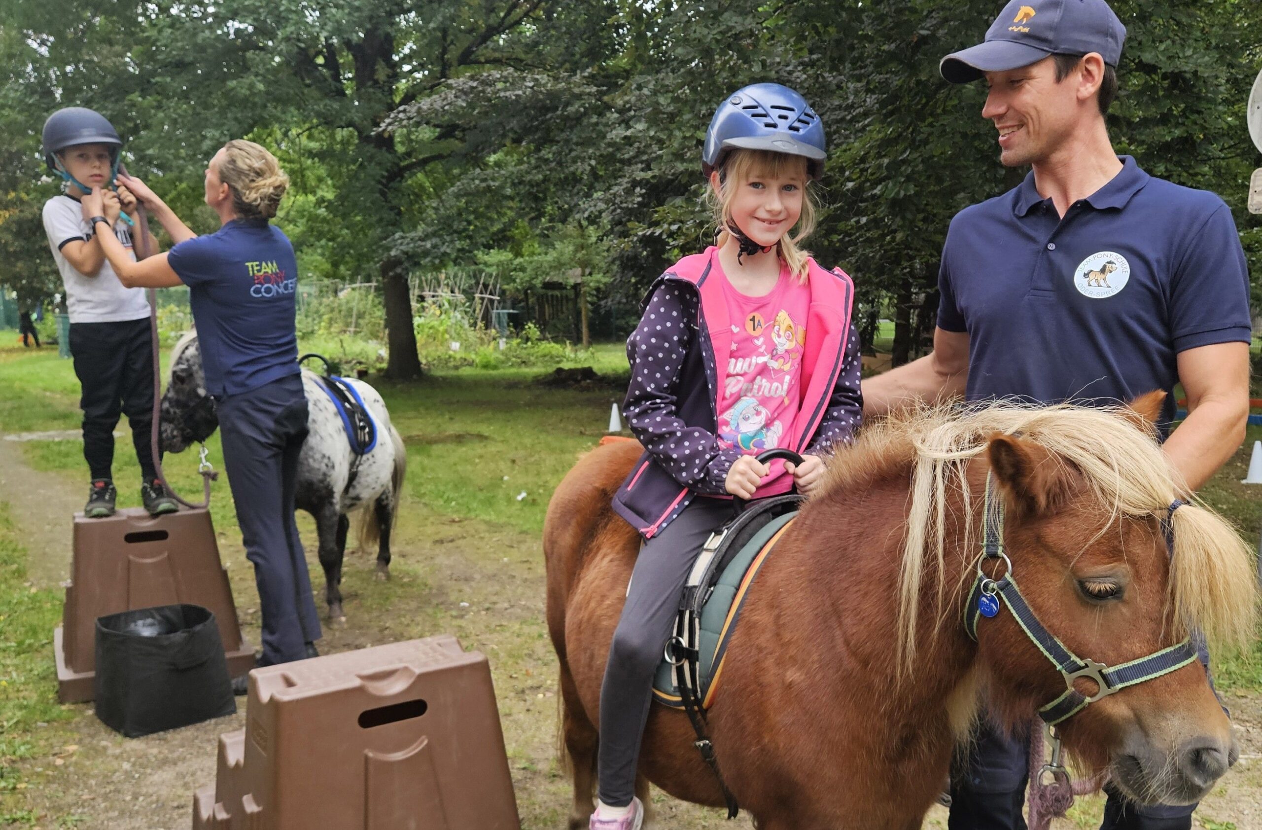 Hoch zu „Mini“-Ross: Lina hat gesichert von Michael Fankhauser vom Team Pony Schule Oder-Spree schon auf dem Rücken von Hetti Platz genommen, während Theodor mit Hilfe von Reitpädagogin Sophie Fankhauser erst noch den Helm schließt. Foto: Anke Beißer