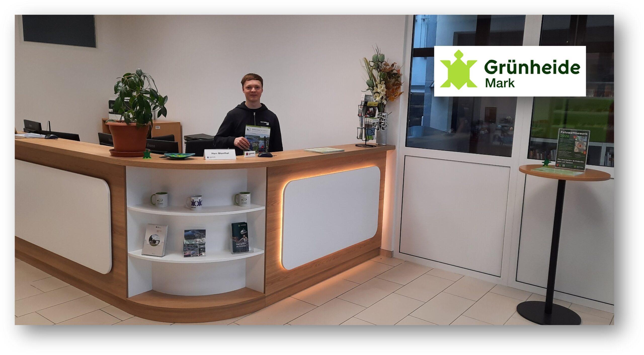 Neuer Empfang: Christopher Manthei, Mitarbeiter der Tourist-Info von Grünheide, hat am Dienstag (31. März) erstmals Besucher im neuen Domizil am Marktplatz - mit modernem, repräsentativen Tresen - willkommen geheißen. Foto: Diana Nolander/Montage: Anke Beißer