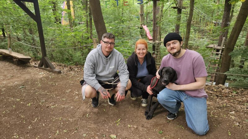 Als Familie ein Team: Sabine Hertam betreibt noch bis Ende September mit ihren Söhnen Tim (rechts) und Robert den Kletterwald am Werlsee Nordstrand. Aktuell immer öfter mit dabei ist Hund Dexter (9 Monate), der sich schon ganz gut an den Trubel gewöhnt hat. Foto: Anke Beißer