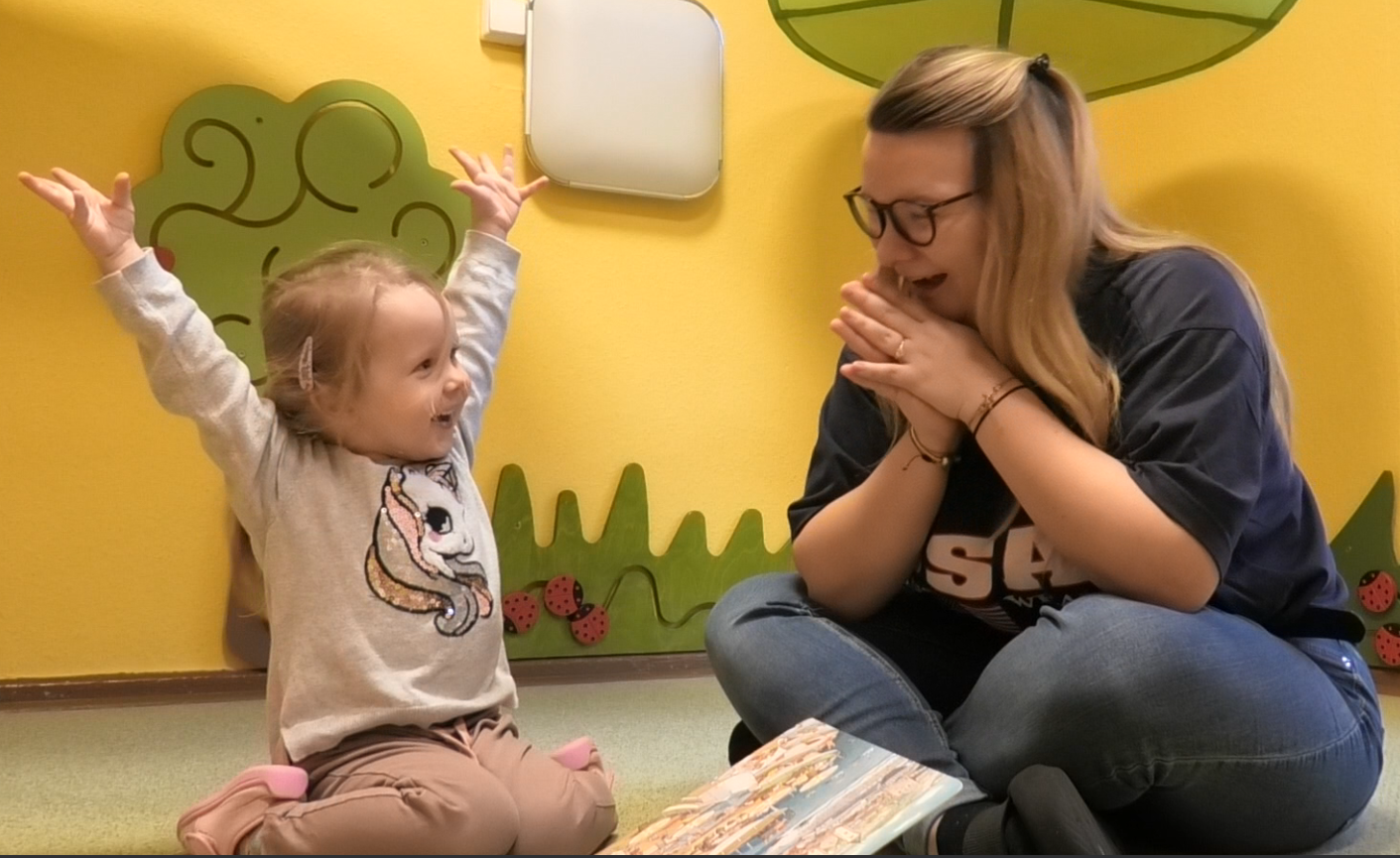 Mate Meo-Element „Folgen – Gefühle benennen“: Clara (3) hat sich ein Bild angeschaut. Eine Entdeckung lässt sie jubeln. Erzieherin Raphaela Scherfling nimmt diese Freude auf und gibt dem Gefühl einen Namen. Foto: Maria Fleischer