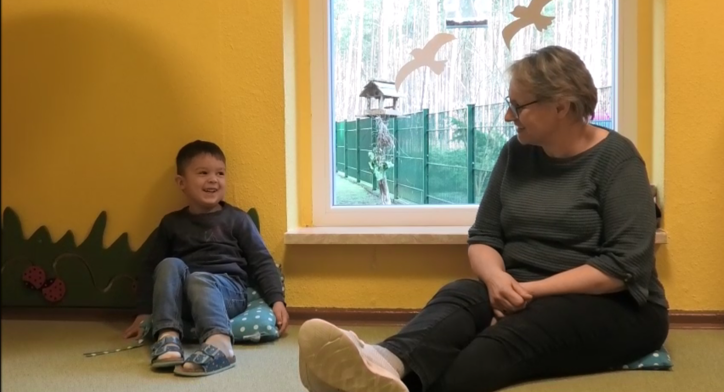 Mate Meo-Element „Folgen - Handlungen benennen“: Die Erzieherin Janin Wagner hat Leano (4) gerade gesagt, as er soeben gemacht hat. Er freut sich über die Aufmerksamkeit, die ihm somit geschenkt wird. Beide lächeln. Foto: Maria Fleischer