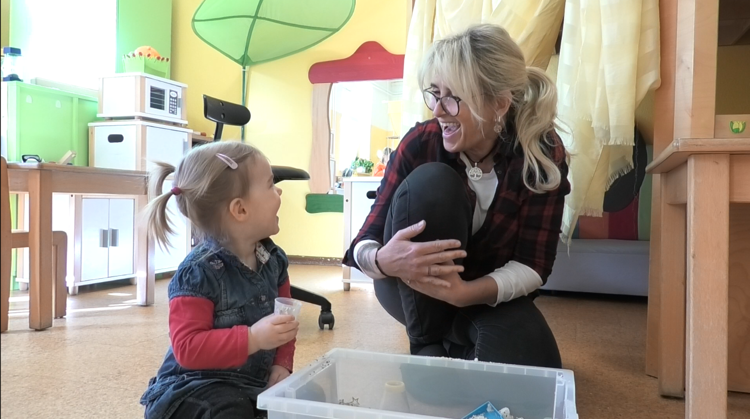 Mate Meo-Element „Sichere Atmosphäre“: Die Erzieherin Beatrice van den Brandt sitzt mit einem einladenden Gesicht, zugewandter Haltung und Blickkontakt bei Chloe (2). Das Mädchen erwidert das mit ebensolcher Offenheit und Freude. Foto: Maria Fleischer